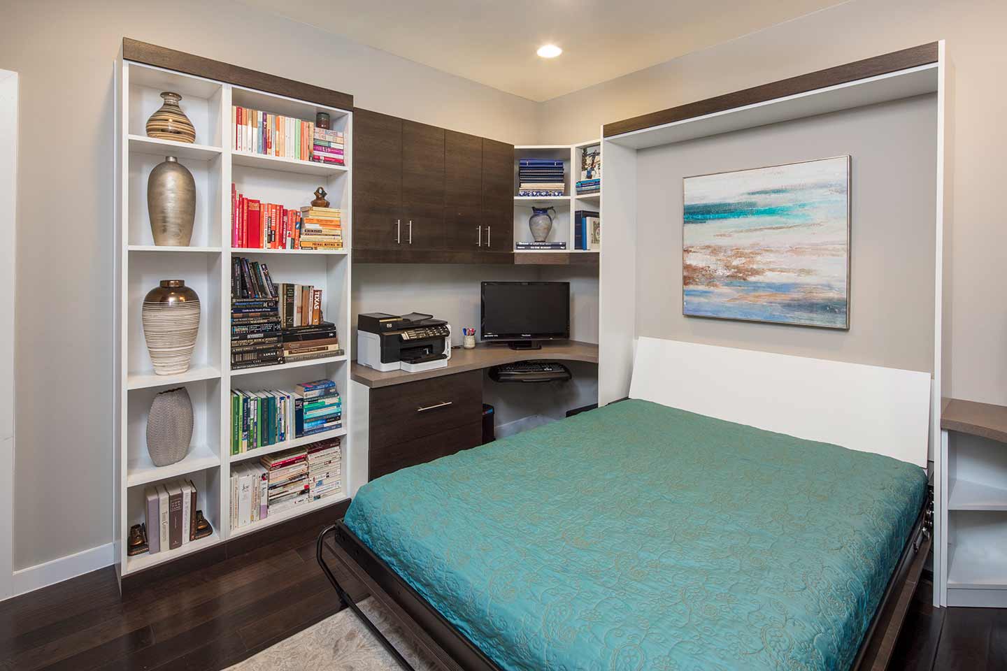 Hybrid room for office and guests featuring a corner desk and queen sized Murphy bed