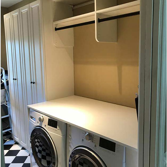 Custom laundry room design with counter above machines and hanging rack for laundry room storage