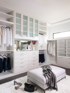 Luxurious and spacious all white custom closet cabinetry with built in storage and display space including rotating closet