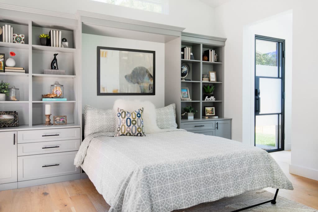 Professionally installed queen size Murphy bed in gray wood with built in bookshelves