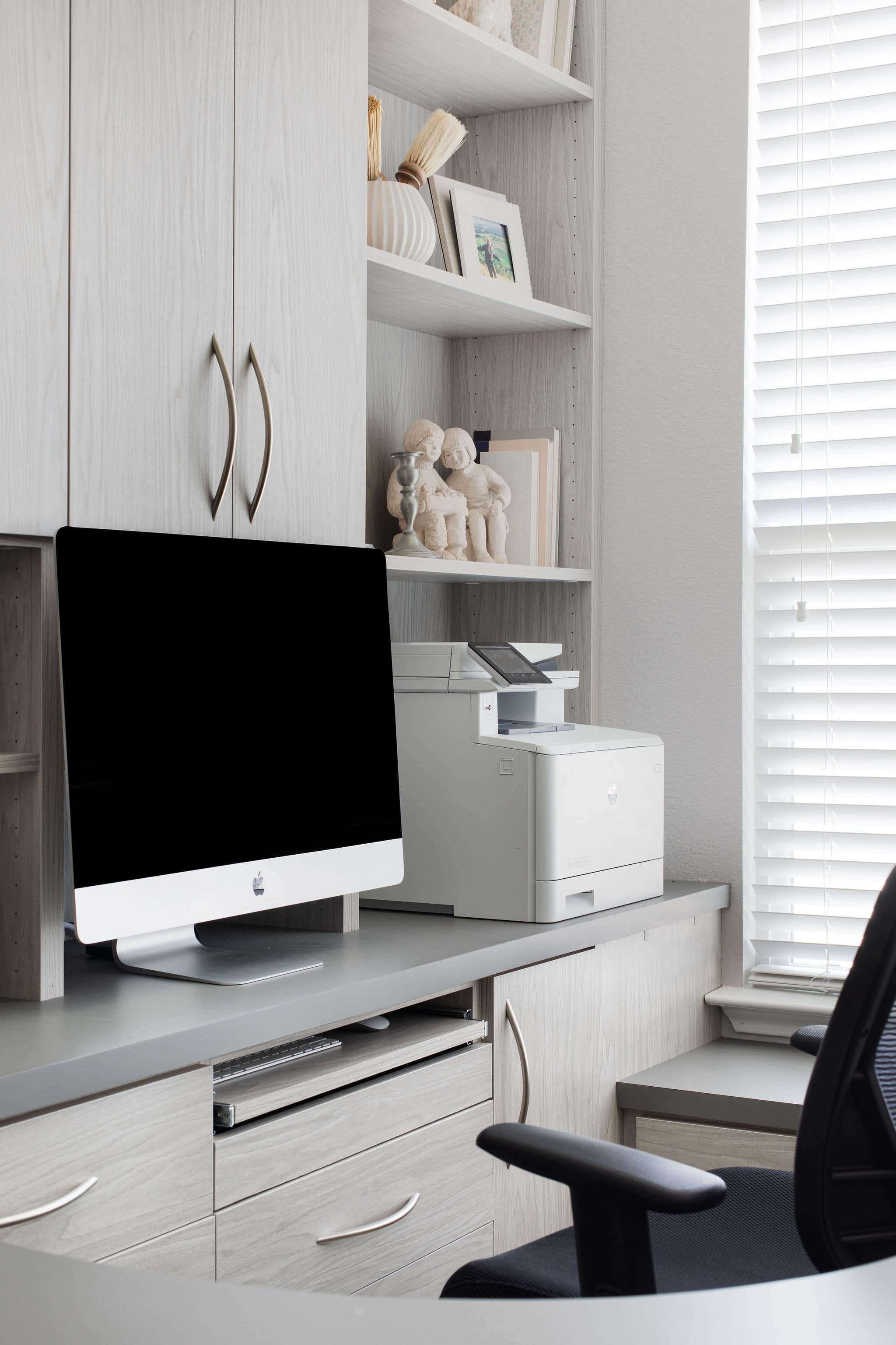 Modern office with natural light featuring custom cabinets for storage and appliances