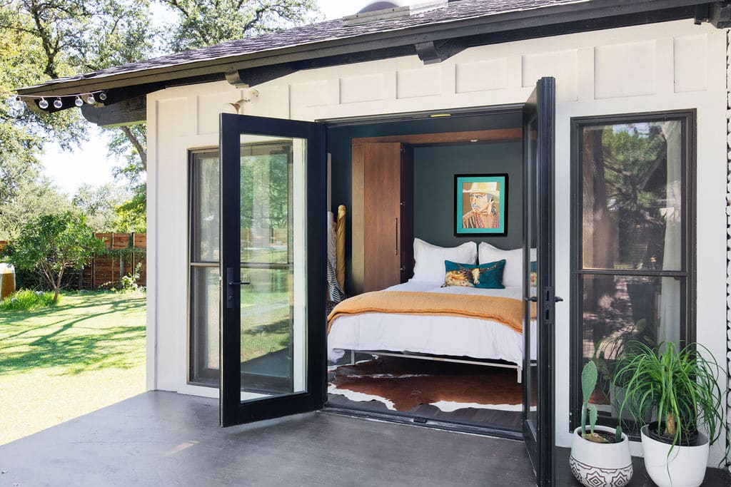 Murphy bed open in a shared office and guest room space with exterior doors opening on to patio 