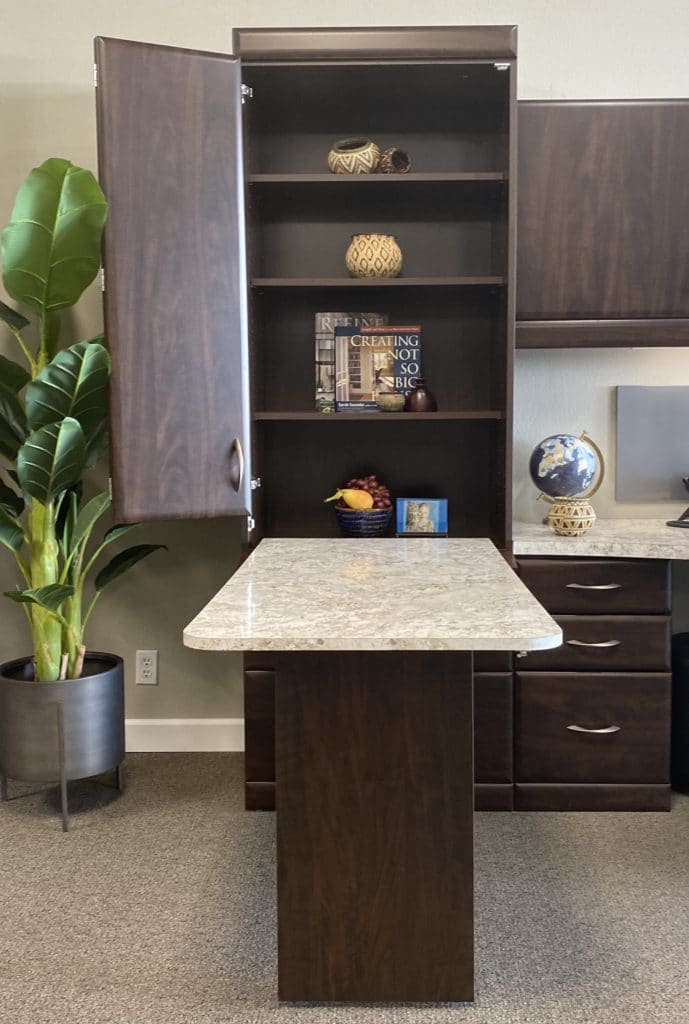 A drop-down desk folds out of a tall white cabinet, providing a convenient home office setup