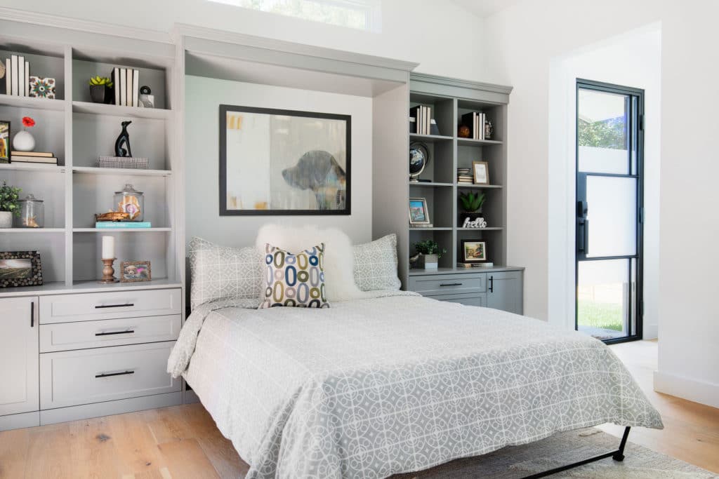 A Murphy bed surrounded by gray custom cabinets is opened and ready to use 