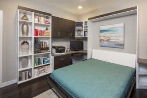 Murphy bed expanded next to desk and bookshelves in home office space 