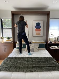 Cyndi hanging bright modern prints above a Murphy bed within the cabinet wall.