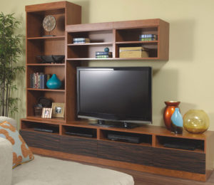 Asymmetrical multi-level free-standing wood media center with bookshelves to the left of and above television set.