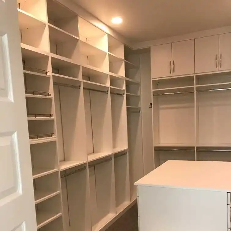 Floor to ceiling white shaker walk-in closet with island.