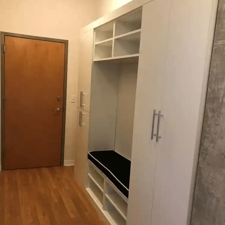 White contemporary mudroom with a bench in the middle.