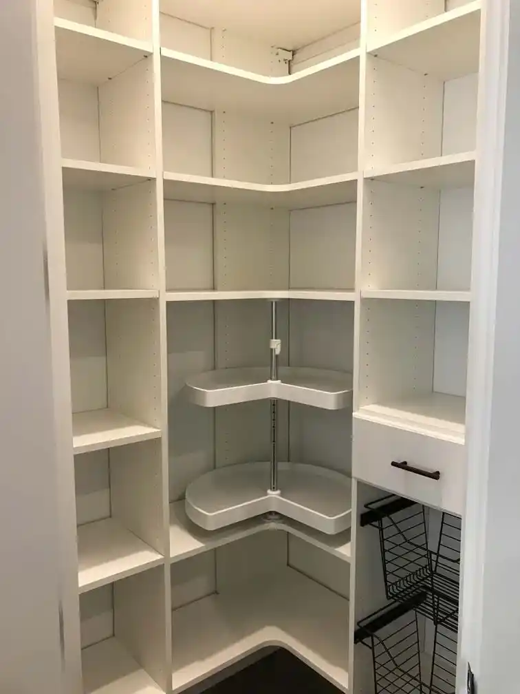 White contemporary pantry with a lazy susan and pull-out baskets.