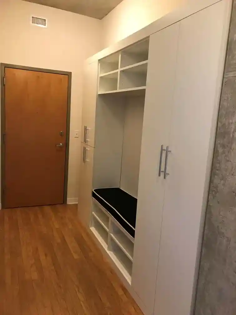 White contemporary mudroom with a bench in the middle.